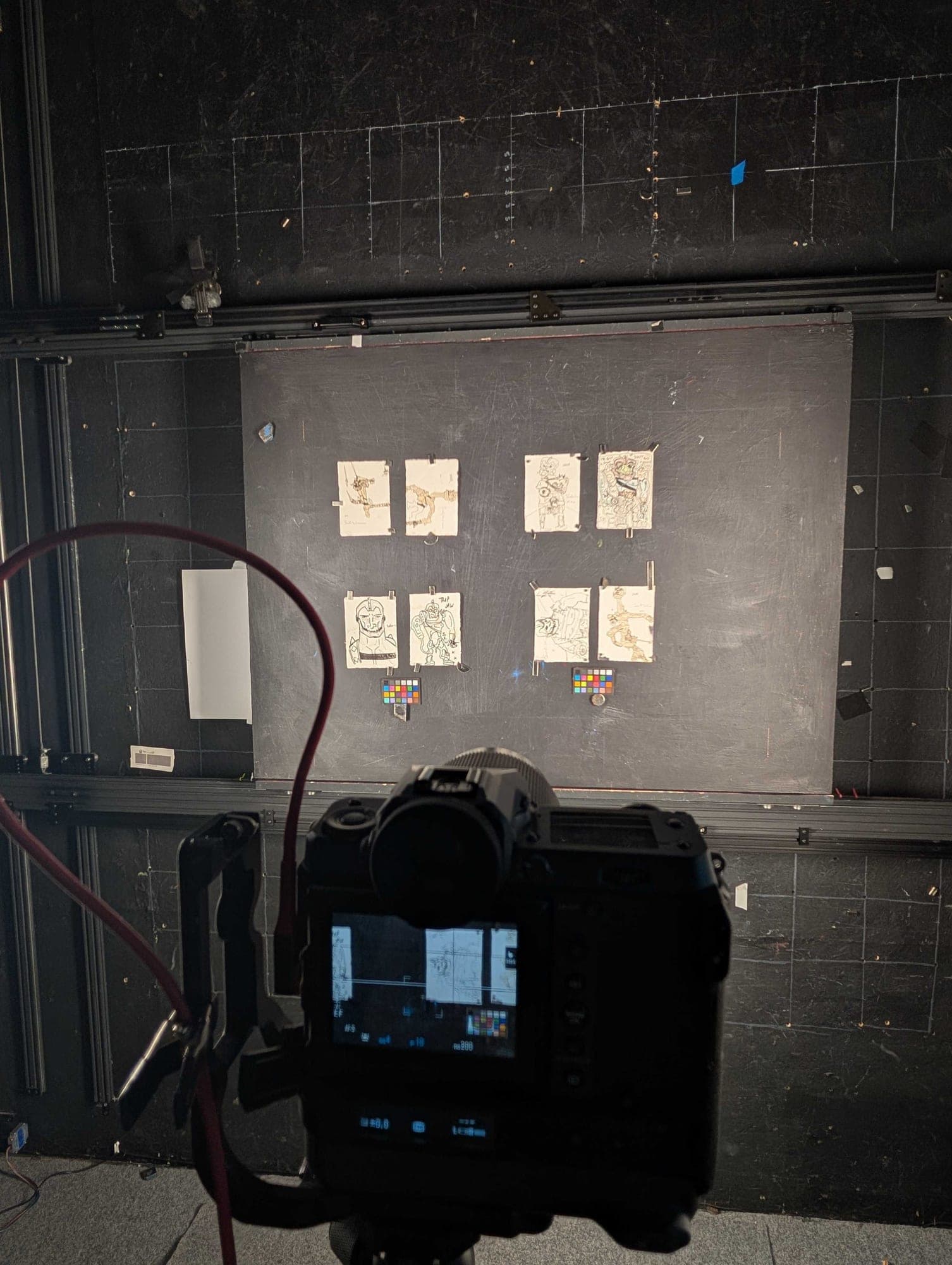 Original Trap Jaw drawings mounted on the black capture wall at the fine art studio, color calibration targets beside them and the medium format camera in the foreground.