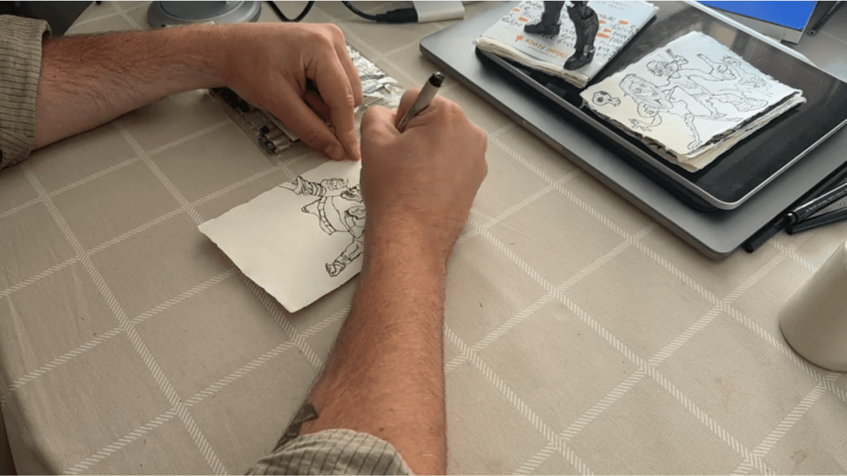 Sam C. Wilson drawing an original piece by hand on deckle-edge paper.
